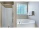Bathroom featuring a soaking tub with a glass block window and a glass framed shower at 204 Southern Style Dr, Holly Springs, NC 27540