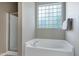 Bathroom featuring a soaking tub with a glass block window and a glass framed shower at 204 Southern Style Dr, Holly Springs, NC 27540