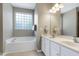 Bright bathroom featuring a soaking tub, double sink vanity, and a large glass block window at 204 Southern Style Dr, Holly Springs, NC 27540