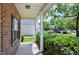 Inviting front porch with brick accents, white columns, and manicured hedges, offering a pleasant entry at 204 Southern Style Dr, Holly Springs, NC 27540