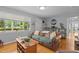 Cozy living room featuring hardwood floors, a leather couch, and a large window overlooking the yard at 2125 Cheek Rd, Durham, NC 27704