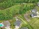 Aerial view of a home's backyard with stone patio and water feature next to golf course and wooded area at 213 Lofty Oak Ln, Holly Springs, NC 27540