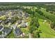 Wide aerial view of a neighborhood with golf course featuring luxurious home with patio and manicured lawns at 213 Lofty Oak Ln, Holly Springs, NC 27540