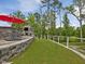 Beautifully landscaped backyard with a stone retaining wall, lush lawn, and a fireplace at 213 Lofty Oak Ln, Holly Springs, NC 27540