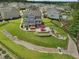 Aerial view of a spacious backyard featuring a stone patio, outdoor kitchen, hot tub, and a decorative rock drainage feature at 213 Lofty Oak Ln, Holly Springs, NC 27540