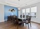 Elegant dining room featuring a modern chandelier, blue accent wall, and seating for eight at 213 Lofty Oak Ln, Holly Springs, NC 27540