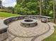 Stone fire pit surrounded by a curved stone wall and patio in a lush backyard setting at 213 Lofty Oak Ln, Holly Springs, NC 27540