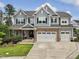 Two-story home featuring gray siding, a stone-accented garage, and a charming covered front porch with stone footers at 213 Lofty Oak Ln, Holly Springs, NC 27540