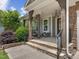 Inviting covered front porch with stone accents and comfortable seating, enhanced by a stylish chandelier at 213 Lofty Oak Ln, Holly Springs, NC 27540
