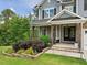 Inviting covered front porch with stone accents and comfortable seating, perfect for relaxing outdoors at 213 Lofty Oak Ln, Holly Springs, NC 27540