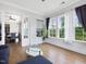 Bright living room with hardwood floors, three large windows, and an open entrance to the breakfast nook at 213 Lofty Oak Ln, Holly Springs, NC 27540