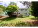 View of the home's backyard with a deck, stairs, lawn, and some foliage at 2441 Deanwood Dr, Raleigh, NC 27615