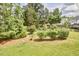 Landscaped backyard with grass, trees, bushes, and garden at 2916 Reynolda Cir, Durham, NC 27712
