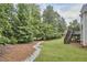 Well-maintained backyard features a wooded area, green lawn, and a staircase to a small porch attached to the home at 2916 Reynolda Cir, Durham, NC 27712