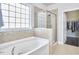 Luxurious bathroom featuring a soaking tub, glass shower, neutral tile, and a walk-in closet at 2916 Reynolda Cir, Durham, NC 27712