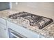 Close-up of a modern gas range cooktop with stainless steel knobs and gray tile backsplash on granite counters at 2916 Reynolda Cir, Durham, NC 27712