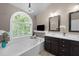 Bathroom featuring a soaking tub under a window, a chandelier, and a double sink vanity at 2921 Imperial Oaks Dr, Raleigh, NC 27614