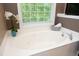 A luxurious white soaking tub with jets sits beneath a bright window offering natural light at 2921 Imperial Oaks Dr, Raleigh, NC 27614