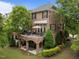 Rear exterior view of brick home with upper deck, covered patio, mature trees, and landscaping at 2921 Imperial Oaks Dr, Raleigh, NC 27614