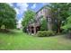 Rear exterior view of brick home with upper deck, covered patio, lush lawn, and manicured landscaping at 2921 Imperial Oaks Dr, Raleigh, NC 27614