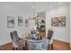 Open dining room with a glass table, upholstered chairs, hardwood floors, chandelier, and decorative wall art at 3 Yancey, Pittsboro, NC 27312