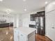 Open kitchen view showcasing stainless steel refrigerator, white island, and seamless connection to the living area at 316 Wellwater Ave, Durham, NC 27703
