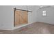 Bedroom with wood-look tile floors, neutral walls, and large sliding barn door at 3323 Cheswick Dr, Raleigh, NC 27609