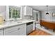Bright kitchen area with stainless dishwasher, white cabinets, and a bay window at 4 Weathergreen Ct, Durham, NC 27713