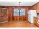 Cozy eat-in kitchen features wood paneling, hardwood floors, and bright window at 411 W Killiegrey St, Lillington, NC 27546