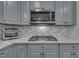 Close-up of modern kitchen with stainless steel appliances, grey cabinets, and granite countertops at 4802 Glenmist Ct, Raleigh, NC 27612