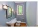 Cozy bathroom featuring a pedestal sink, wood flooring, and a window offering natural light at 5314 Taproot Ln, Durham, NC 27705