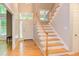 Bright foyer with hardwood floors, staircase with wood railing, transom window, and white front door at 5314 Taproot Ln, Durham, NC 27705