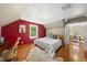 Bright bedroom with hardwood floors, red accent wall, and an open doorway to another room at 5513 Doemont Dr, Apex, NC 27539