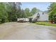White exterior with large driveway, rear stairs, and a wood pile, surrounded by greenery at 5513 Doemont Dr, Apex, NC 27539