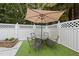 Cozy outdoor patio with green turf and a white lattice fence featuring an umbrella and table with four chairs at 5513 Doemont Dr, Apex, NC 27539