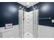 Enclosed shower with white tile and glass doors, complemented by dark blue walls in this modern bathroom at 5513 Doemont Dr, Apex, NC 27539