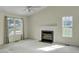 Inviting living room featuring a fireplace, natural light from large windows, and neutral carpeting at 5849 Rocking Chair Dr, Youngsville, NC 27596