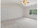 Bright bedroom with neutral carpet, a ceiling fan, and a view of the neighborhood at 5940 Brambleton Ave, Raleigh, NC 27610