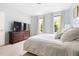 Spacious bedroom with a large bed, wood dresser with TV, and light-filled windows at 601 Culpepper Ct, Durham, NC 27712