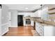 Renovated kitchen boasts white cabinetry, stainless appliances, and hardwood flooring at 6513 Hearthstone Dr, Raleigh, NC 27615