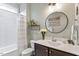 Well-lit bathroom featuring a shower-tub combination, modern vanity, and stylish round mirror and decor at 813 Whitley Way, Wendell, NC 27591