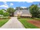 Beautiful brick home with lush green lawn, mature trees and long driveway on a partially cloudy day at 8904 Milden Hall Ct, Raleigh, NC 27615