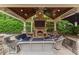 Outdoor pavilion with stone fireplace, TV, kitchen area, comfortable seating, and tongue-and-groove ceiling at 8904 Milden Hall Ct, Raleigh, NC 27615