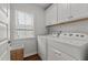 Well-organized laundry room with modern washer and dryer, overhead cabinets, and a window for natural light at 8925 Lee Brown Ridge Dr, Wake Forest, NC 27587
