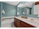 Bright bathroom featuring a double sink vanity with white countertop and a separate tub with tiled surround at 9900 Two Robins Ct, Raleigh, NC 27613