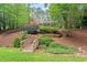 Front exterior featuring landscaped yard, complemented by a charming bridge and mature trees at 9900 Two Robins Ct, Raleigh, NC 27613