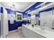 A blue and white bathroom features dual sinks, a large mirror, vanity, and a window with natural light at 10317 Roadstead W Way, Raleigh, NC 27613