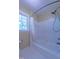 Bathroom with white tile walls, a bathtub and shower combo, and a window at 104 Tutbury Pl, Cary, NC 27519