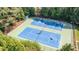 Aerial view of two tennis courts, reflecting the sky, nestled amongst the trees at 104 Tutbury Pl, Cary, NC 27519
