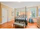 Bedroom features a four-poster bed, hardwood floors, natural light, and neutral paint at 10540 Byrum Woods Dr, Raleigh, NC 27613